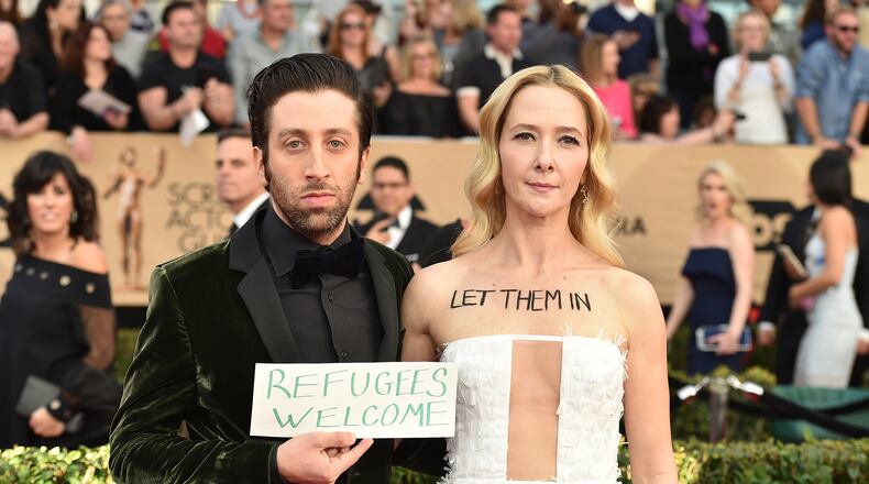 Simon Helberg, left, and Jocelyn Towne display protest signs against the U.S. policy of temporarily barring refugees and citizens of seven predominantly Muslim countries, at the 23rd annual Screen Actors Guild Awards at the Shrine Auditorium & Expo Hall on Sunday, Jan. 29, 2017, in Los Angeles. (Photo by Jordan Strauss/Invision/AP)