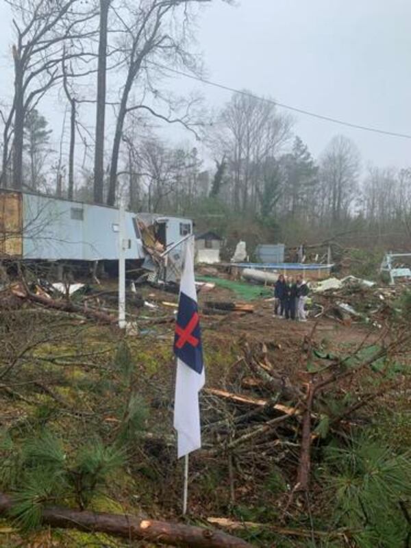 A wooden cross and a Christian flag remain standing after a tornado blew a tree onto Joanne Mathis' home. (Photo Courtesy of Sharon Dowdy Cruse)