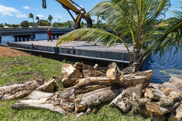 Workers with Arbor Tree and Land in West Palm Beach, secure a barge on the C-15 in Delray Beach, Florida, May 8, 2018. The SFWMD will be clearing banks of trees and brush along the canal to prevent flooding during the hurricane season. (Greg Lovett / The Palm Beach Post)