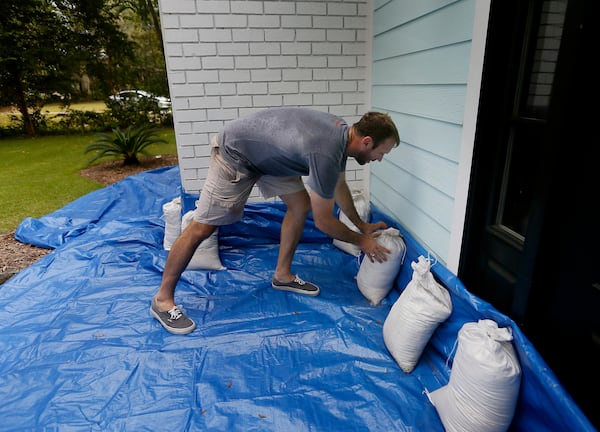 FILE - Stewart Thomason places sandbags that he used for previous hurricanes and tarp to prevent the flooding from rain at his home on the Isle of Palms, S.C. ahead of Hurricane Florence, on Wednesday, Sept. 12, 2018. (Grace Beahm Alford/The Post And Courier via AP,File)