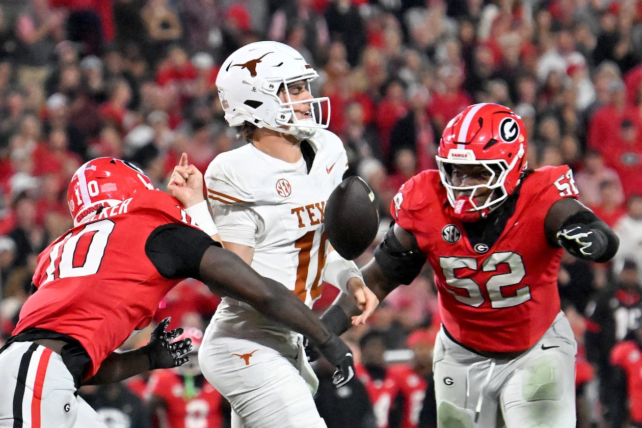 Georgia linebacker Zayden Walker (left) hits Texas quarterback Arch Manning (center), causing a fumble during the second half Saturday, Nov. 15, 2025, at Sanford Stadium in Athens. The Longhorns recovered the fumble. (Hyosub Shin/AJC)
