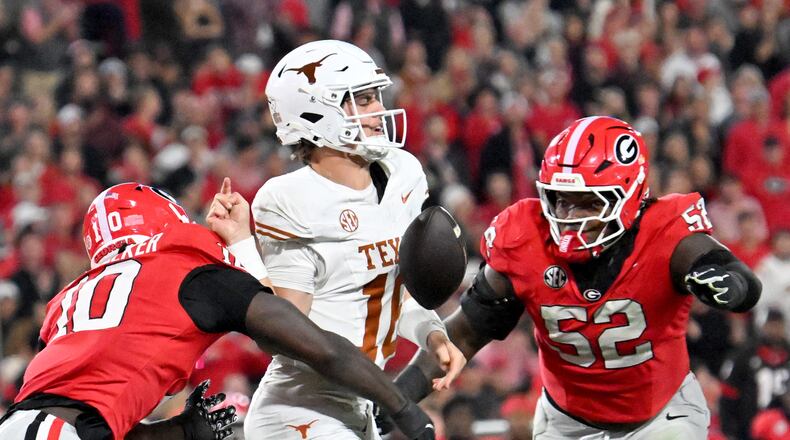 Georgia linebacker Zayden Walker (left) hits Texas quarterback Arch Manning (center), causing a fumble during the second half Saturday, Nov. 15, 2025, at Sanford Stadium in Athens. The Longhorns recovered the fumble. (Hyosub Shin/AJC)