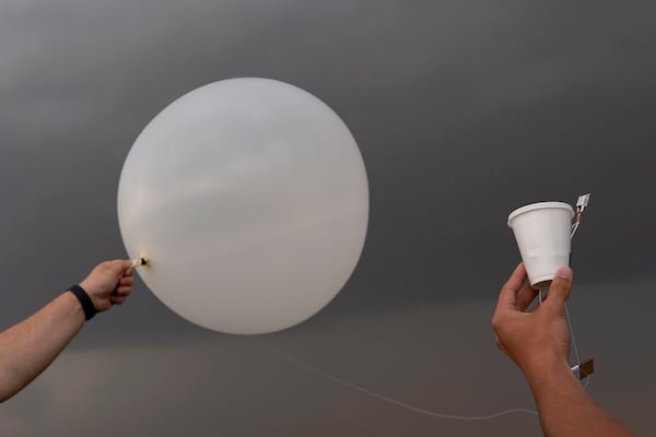 Red team and Project ICECHIP members Wyatt Ficek, left, and Ethan Mok, right, release a latex weather balloon with an attached instrument called a windsond into the inflow region of a storm to collect data during a Project ICECHIP operation Thursday, June 5, 2025, near Morton, Texas. (AP Photo/Carolyn Kaster)