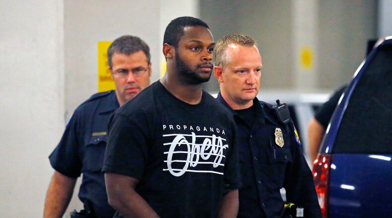Phoenix police officers escort Arizona Cardinals running back Jonathan Dwyer, to the 4th Avenue Jail following his arrest, Wednesday, Sept. 17, 2014 in Phoenix. Arizona Cardinals running back Jonathan Dwyer was arrested Wednesday on aggravated assault charges in connection with two altercations at his home in July involving a woman and an 18-month-old child, the latest in a string of such cases involving NFL players.(AP Photo/The Arizona Republic, David Kadlubowski)
