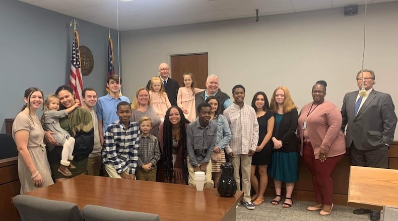 The Rager family poses for a photograph with Cobb County Superior Court Judge Stephen Schuster, along with their case manager and attorney, on the day they adopted two children. The two recently adopted girls sit on the bench below the judge. E. Hailey, 6, poses next to Lisa Rager. A. Faith, 8, has her arm around Wesley Rager. Photo courtesy of Lisa Rager.