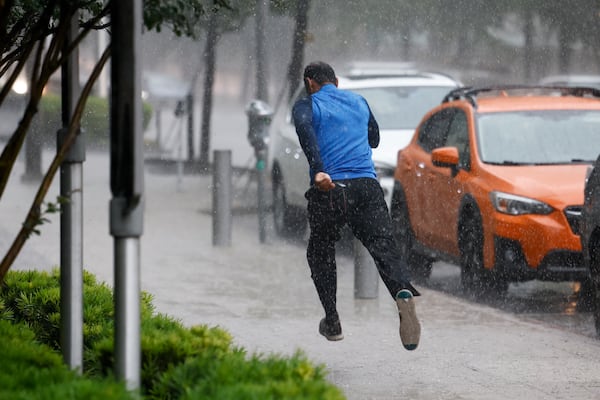 A man runs down the sidewalk along Commerce Street while heavy rain fall in downtown Dallas, Wednesday, April 30, 2025, and a flash flood warning was issued for parts of North Texas through this afternoon. (Elías Valverde II/The Dallas Morning News via AP)
