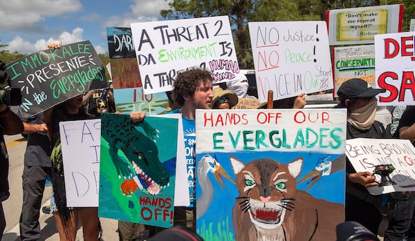 Protesters march outside the Dade-Collier Training and Transition Airport where President Donald Trump appeared, Tuesday, July 1, 2025, in Ochopee, Fla. (AP Photo/Michael Laughlin)