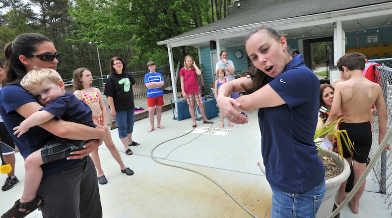 **LEAD PHOTO**April 11, 2013 Lilburn - Coach Erica Porten (right) talks to her swim team members and parents as they clean up the outdoor swimming pool in Huntington subdivision in Lilburn on Thursday, April 11, 2013. Here she was demonstrating a move they could use in the fund-raising video they were going to make. There was just one problem when long-time swimming coach Erica Porten took over Gwinnett County's Berkmar High School swim team earlier this year - more than half of her team didn't know how to swim. Porten is now starting the only summer swim program for kids in the Berkmar school cluster and is competing for a $25,000 grant that is needed to renovate the program's home pool in Lilburn's Huntington subdivision and pay for the gear necessary to compete in a county swim league that is well-established with many huge and well-funded teams. HYOSUB SHIN / HSHIN@AJC.COM