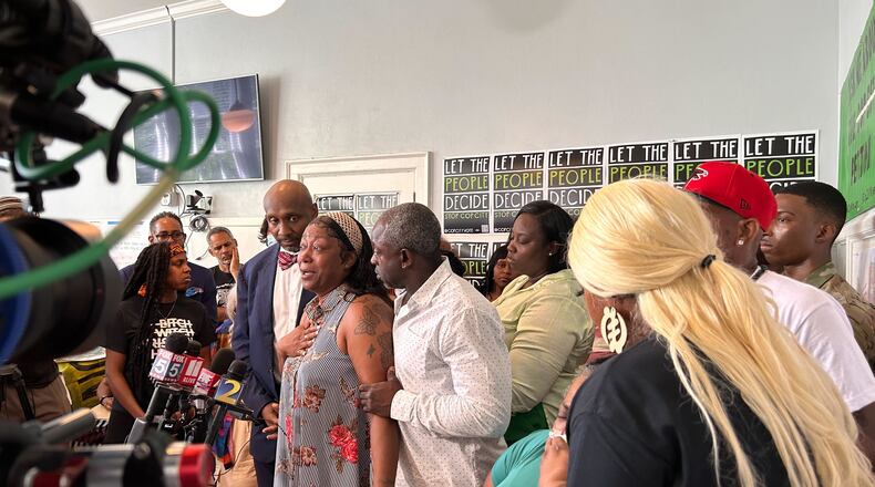 Arnitra Fallins speaks at a recent news conference, more than a week after her father died while being arrested in Atlanta. She stands next to her brother, Johnny Hollman Jr., and in front of several other family members.