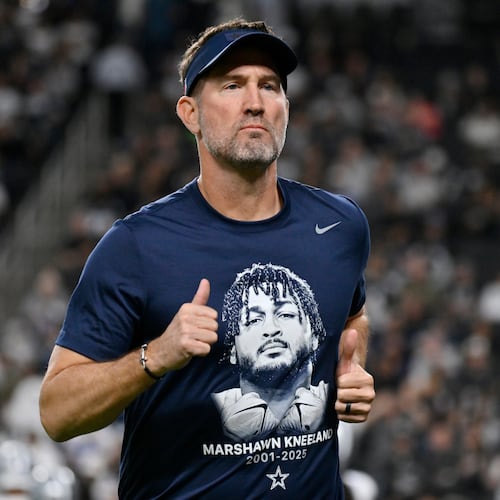 Dallas Cowboys head coach Brian Schottenheimer wears a tribute t-shirt of Cowboys' Marshawn Kneeland prior to an NFL football game against the Las Vegas Raiders Monday, Nov. 17, 2025, in Las Vegas, in memory of Kneeland who passed away earlier this month. (AP Photo/David Becker)
