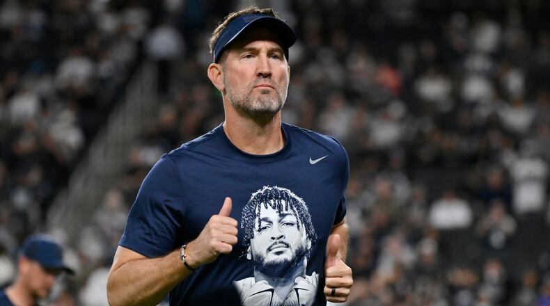Dallas Cowboys head coach Brian Schottenheimer wears a tribute t-shirt of Cowboys' Marshawn Kneeland prior to an NFL football game against the Las Vegas Raiders Monday, Nov. 17, 2025, in Las Vegas, in memory of Kneeland who passed away earlier this month. (AP Photo/David Becker)