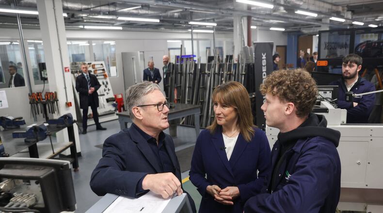 Britain's Prime Minister Keir Starmer, left, talks with a student, next to Britain's Chancellor of the Exchequer, Rachel Reeves, center, at the engineering workshop at Coleg Menai, during his visit to announce Wylfa on Anglesey, an island in North Wales, as the location for the country's first small modular reactor in Llangefni, North Wales, Britain, Thursday, Nov. 13, 2025. (Temilade Adelaja/Pool Photo via AP)