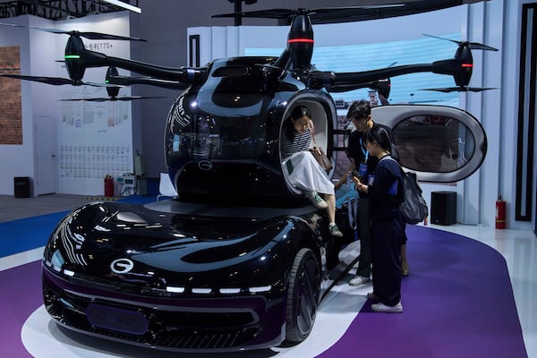 Visitors try out the Govy AirCar, an autonomous one passenger eVTOL aircraft and roadable prototype vehicle by Guangzhou Automobile Group Co., Ltd. on display at the 3rd Exhibition of Technology and Education in Civil Aviation as China promoting the low-altitude economy, in Beijing, Tuesday, May 27, 2025. (AP Photo/Andy Wong)