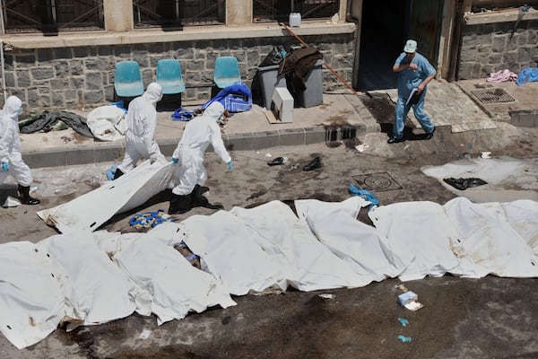 Morgue workers place the bodies of unidentified people killed during clashes between Bedouin clans and Druze militias, into plastic bags outside the National Hospital in Sweida, Syria, Monday, July 21, 2025. (AP Photo/Fahd Kiwan)
