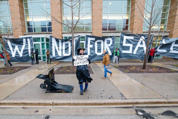 Protesters hold signs as people arrive for a town hall with Elon Musk, Sunday, March 30, 2025, in Green Bay, Wis. (AP Photo/Jeffrey Phelps)