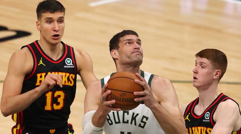 Hawks guards Bogdan Bogdanovic (left) and Kevin Huerter can't stop Bucks center Brook Lopez from going to the basket for two of his 33 points during the first quarter in game 5 of the NBA Eastern Conference Finals on Thursday, July 1, 2021, in Milwaukee.