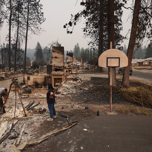 From left, homeowner Al Acosta, his son Louis Acosta, daughter Renee Stewart and son-in-law Jamie Stewart look through the remains of Al's home after a wildfire hit the northern part of Spokane, Wash., Monday, Aug. 3, 2026. (AP Photo/Lindsey Wasson)