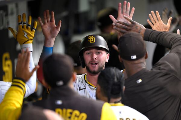 San Diego Padres' Jackson Merrill is congratulated in the dugout after scoring on a three RBI triple by Tyler Wade, not pictured, during the third inning of a baseball game against the Los Angeles Dodgers, Monday, June 9, 2025, in San Diego. (AP Photo/Orlando Ramirez)