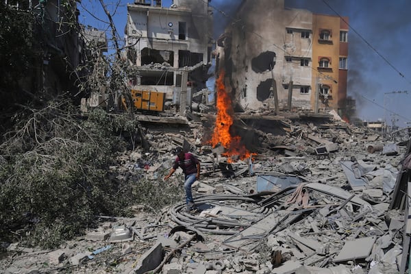 A Palestinian man walks across the rubble of a building destroyed by an Israeli strike in Deir al-Balah, central Gaza Strip, Monday, June 16, 2025. (AP Photo/Abdel Kareem Hana)