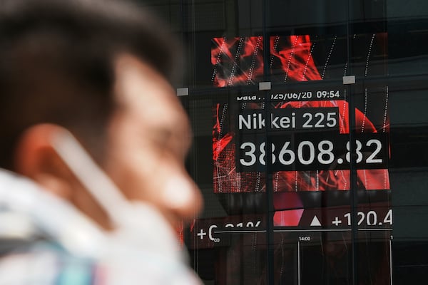 A person stands in front of an electronic stock board showing Japan's Nikkei index at a securities firm Friday, June 20, 2025, in Tokyo. (AP Photo/Eugene Hoshiko)