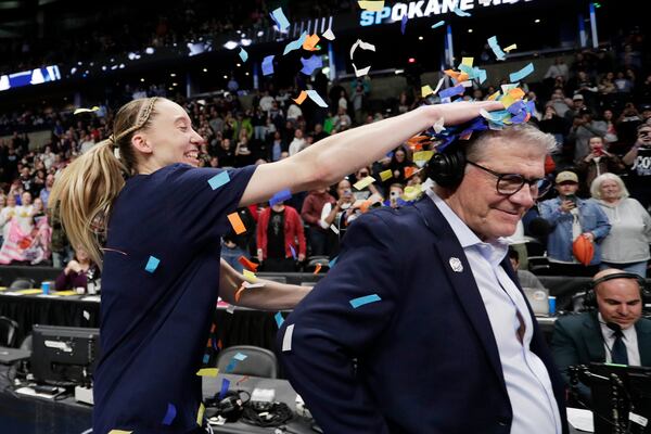 UConn guard Paige Bueckers, left, places confetti onto head coach Geno Auriemma, front right, after the team's win over Southern California in the Elite Eight of the NCAA college basketball tournament, Monday, March 31, 2025, in Spokane, Wash. (AP Photo/Young Kwak)