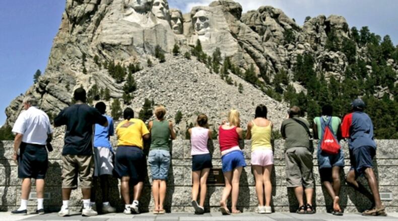 Visitors watch workers pressure-wash the granite faces of George Washington (from left), Thomas Jefferson, Theodore Roosevelt and Abraham Lincoln at Mount Rushmore National Memorial in South Dakota. (Charlie Riedel / AP file)