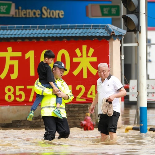In this photo released by Xinhua News Agency, a police officer holds a boy as he wades through a flooded street in Duyun city, southwestern China's Guizhou Province on Tuesday, May 19, 2026. (Xiao Wei/Xinhua via AP)