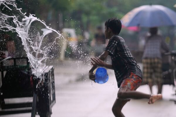 A boy throws water to revelers on a tri-cycle during the first day of annual traditional water festival also known as "Thingyan", in Yangon, Myanmar, Sunday, April 13, 2025. (AP Photo/Thein Zaw)