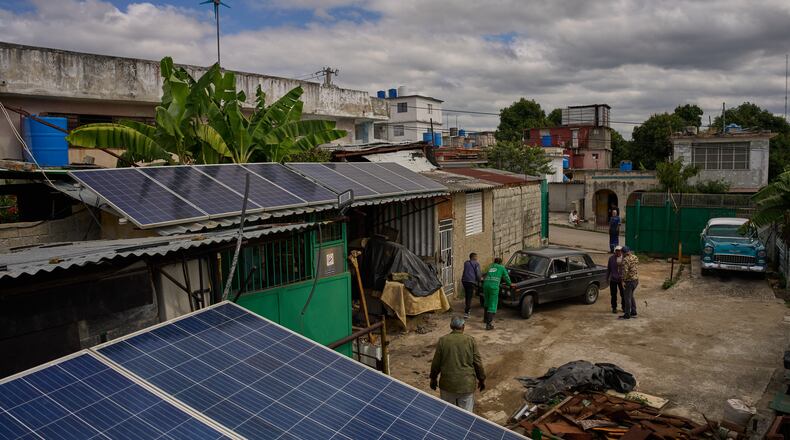 Solar panels cover the roof at the home of Felix Jose Morfi where mechanics push his broken down Lada car in Regla, Havana province, Cuba, Thursday, Jan. 29, 2026. (AP Photo/Ramon Espinosa)