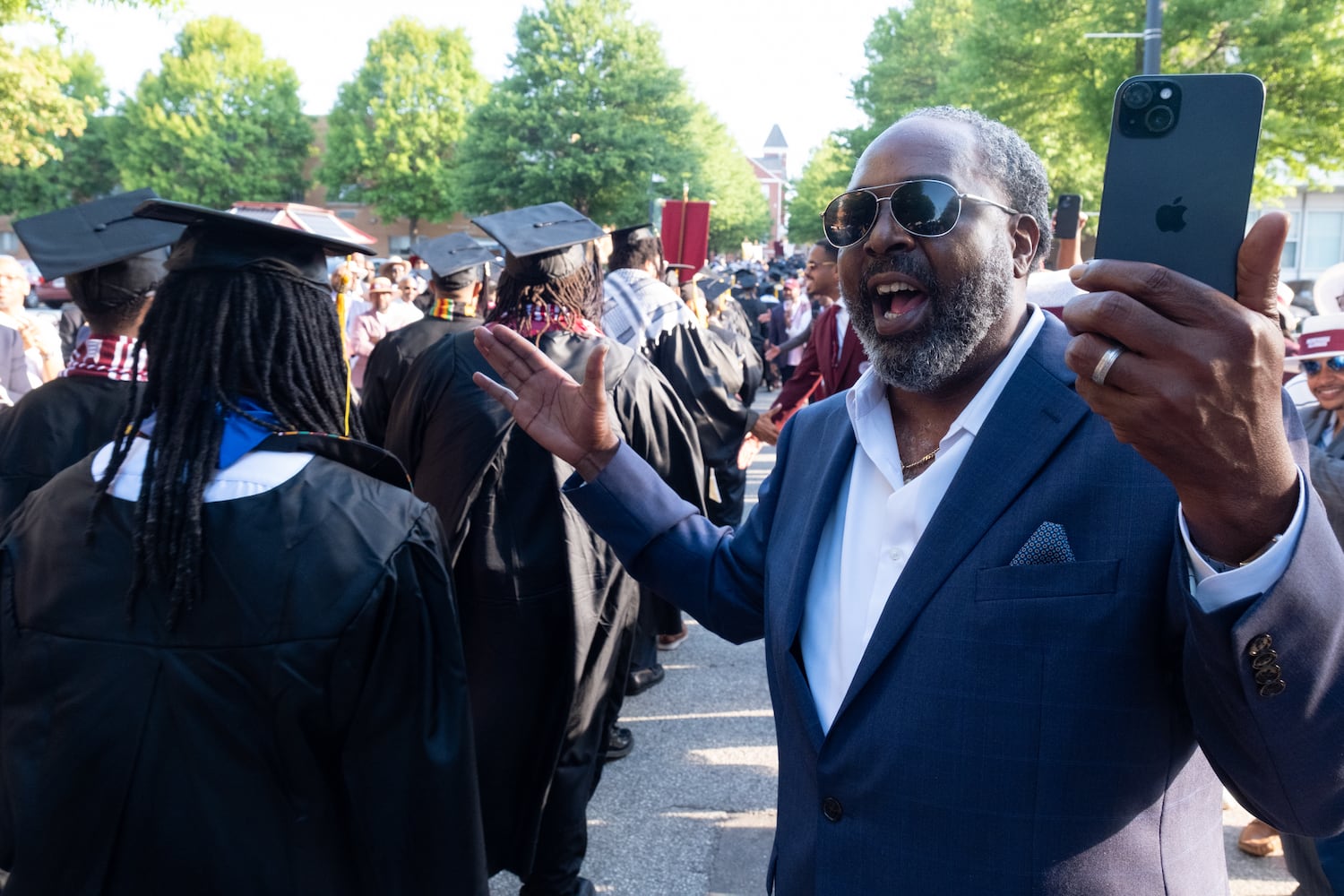 Devotes Jones, Morehouse College class of 1995, cheers on graduates as they walk the alumni corridor on the way to commencement Sunday, May 17, 2026. (Ben Gray for the AJC)