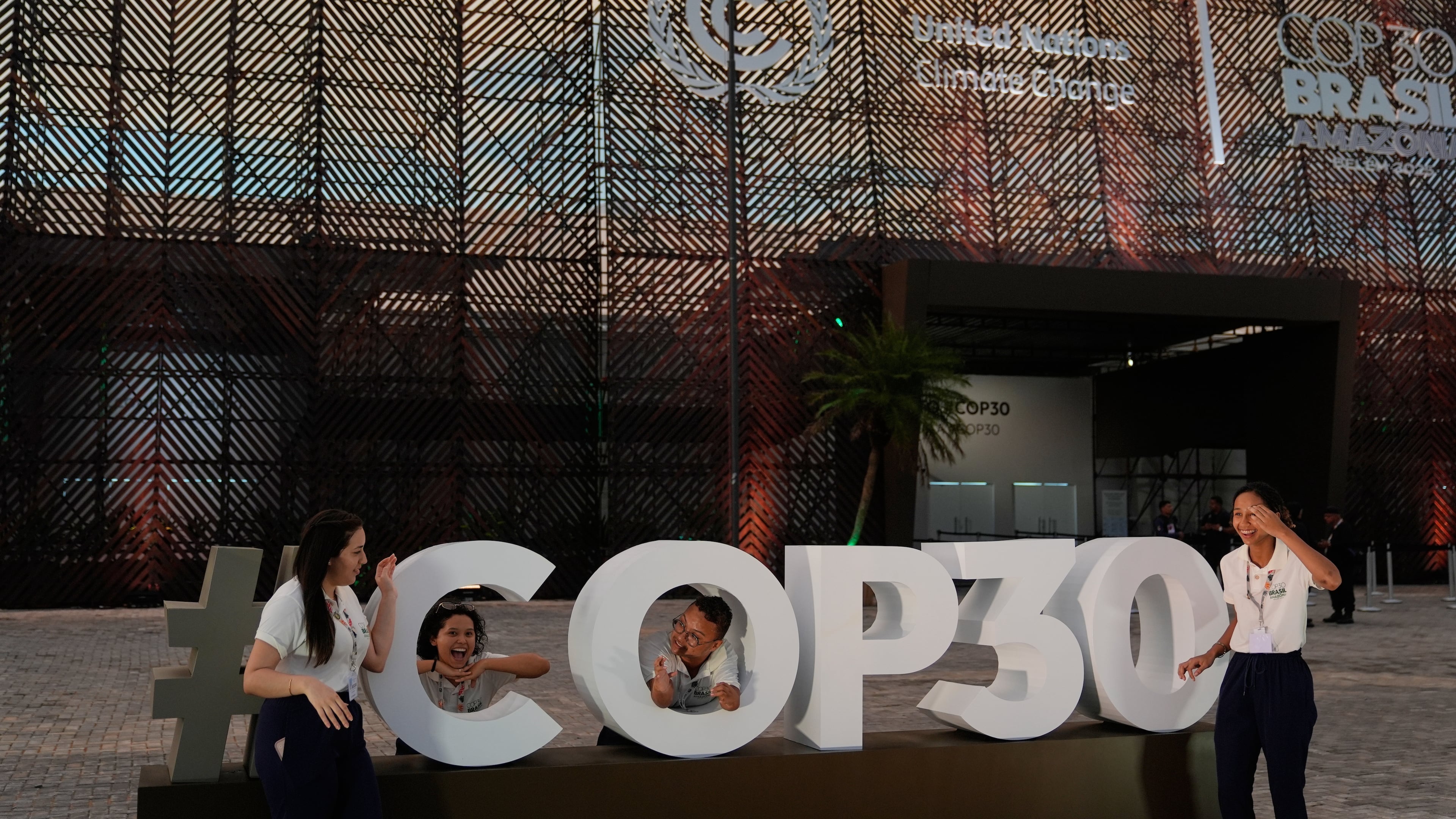 People pose for photos outside the venue for the COP30 U.N. Climate Summit, Saturday, Nov. 8, 2025, in Belem, Brazil. (AP Photo/Fernando Llano)