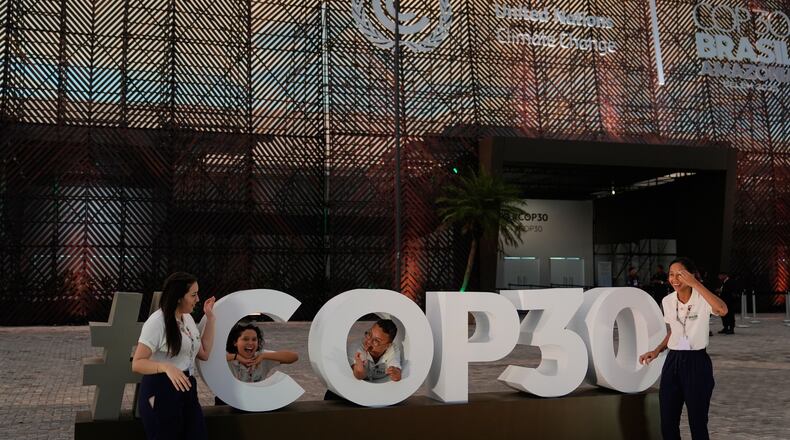 People pose for photos outside the venue for the COP30 U.N. Climate Summit, Saturday, Nov. 8, 2025, in Belem, Brazil. (AP Photo/Fernando Llano)