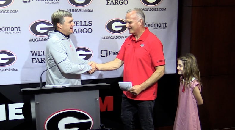 Georgia coach Kirby Smart (left) welcomes former Bulldogs coach Mark Richt and his granddaughter Jadyn to Monday's press conference. Scheduled to discuss the No. 1 Bulldogs' game against No. 22 Kentucky on Saturday, Richt borrowed the podium to promote his Oct. 18 fundraiser event, "Chick-fil-A Dawg Bowl 2023," which will raise money for Parkinson's and Chrone's disease research.