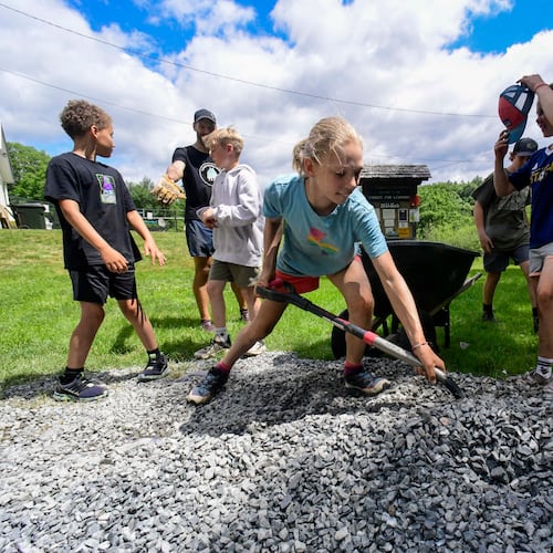 Lena Quintal, 10, a rising sixth-grader at Putney, Vt., Central School, shovels rocks into a wheelbarrow with other students as part of the school's Community Schools Initiative on Juneteenth on Friday, June 19, 2026. (Kristopher Radder /The Brattleboro Reformer via AP)