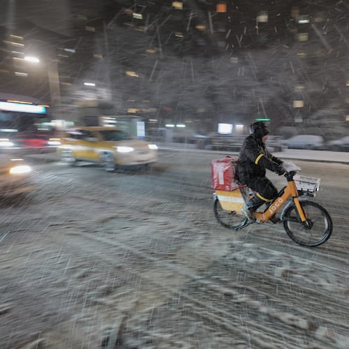 A delivery cyclist travels along 14th Street as snow falls in the Alphabet City neighborhood of New York, Sunday evening, Feb. 22, 2026. (AP Photo/Patrick Sison)
