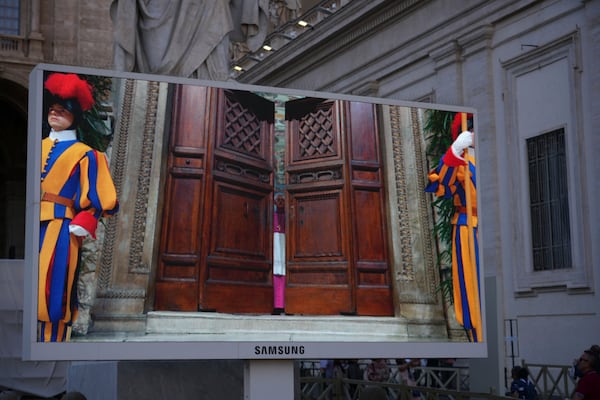 A giant screen shows Swiss Guards standing as the door of the Sistine Chapel is being closed, during the conclave to elect a new pope, at the Vatican, Wednesday, May 7, 2025. (AP Photo/Andrew Medichini)