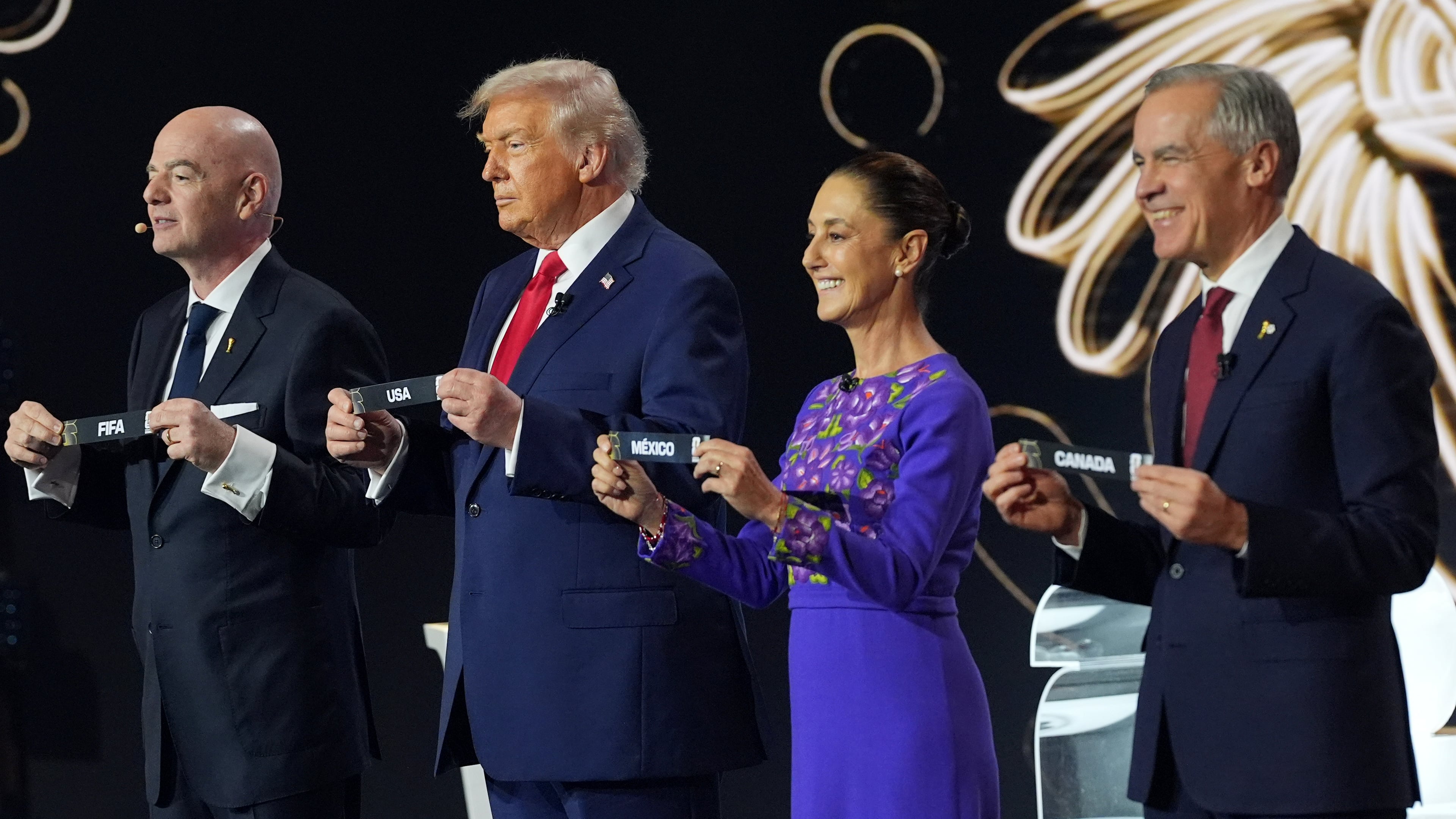Canadian Prime Minister Mark Carney, Mexican President Claudia Sheinbaum, President Donald Trump and FIFA President Gianni Infantino hold up country names during the draw for the 2026 soccer World Cup at the Kennedy Center in Washington, Friday, Dec. 5, 2025. (AP Photo/Jacquelyn Martin)
