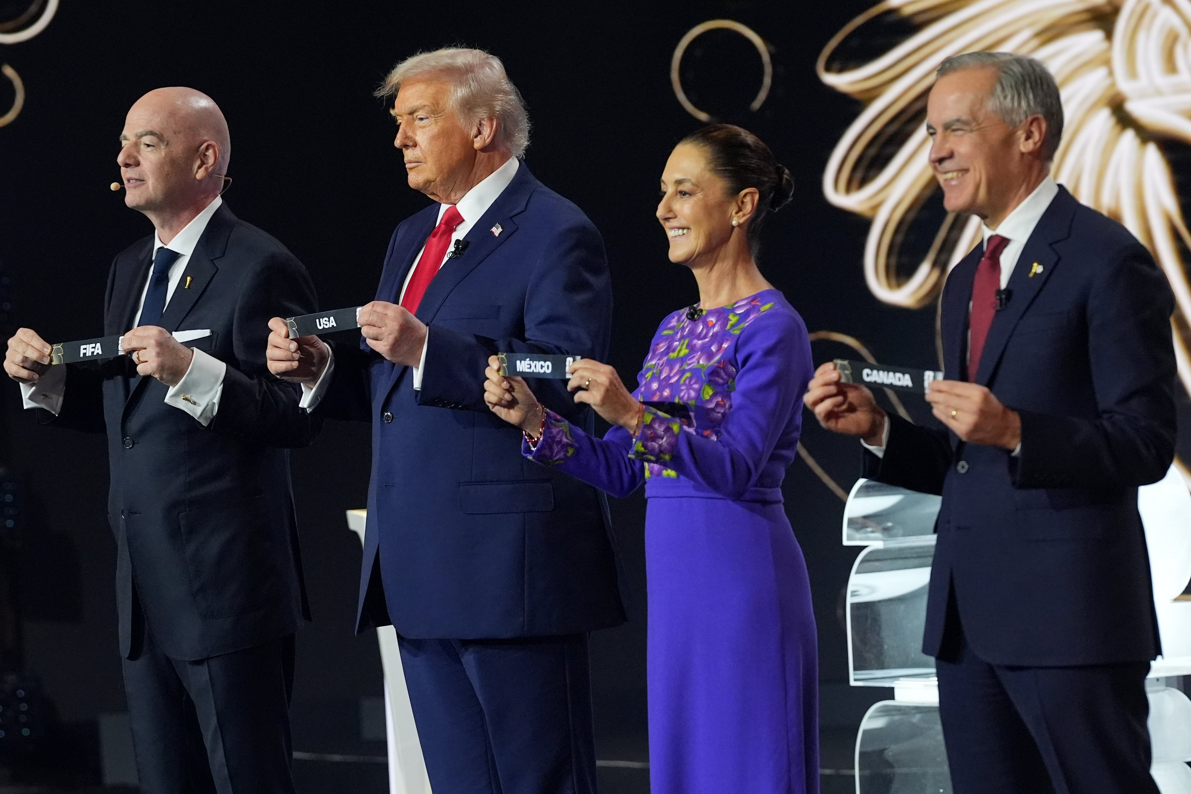 Canadian Prime Minister Mark Carney, Mexican President Claudia Sheinbaum, President Donald Trump and FIFA President Gianni Infantino hold up country names during the draw for the 2026 soccer World Cup at the Kennedy Center in Washington, Friday, Dec. 5, 2025. (AP Photo/Jacquelyn Martin)
