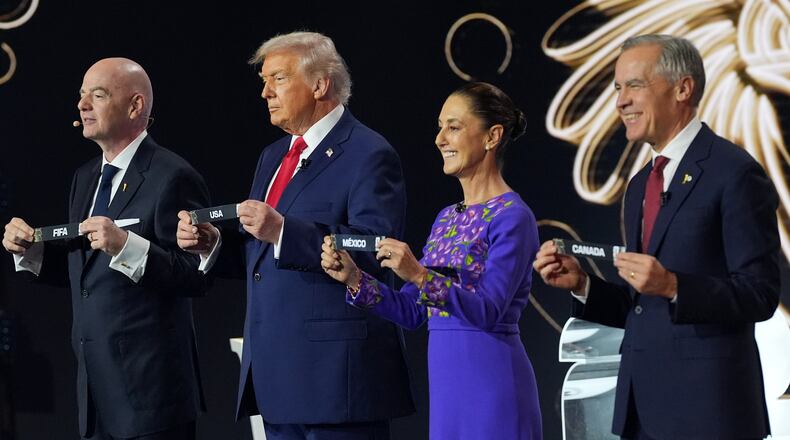 Canadian Prime Minister Mark Carney, Mexican President Claudia Sheinbaum, President Donald Trump and FIFA President Gianni Infantino hold up country names during the draw for the 2026 soccer World Cup at the Kennedy Center in Washington, Friday, Dec. 5, 2025. (AP Photo/Jacquelyn Martin)