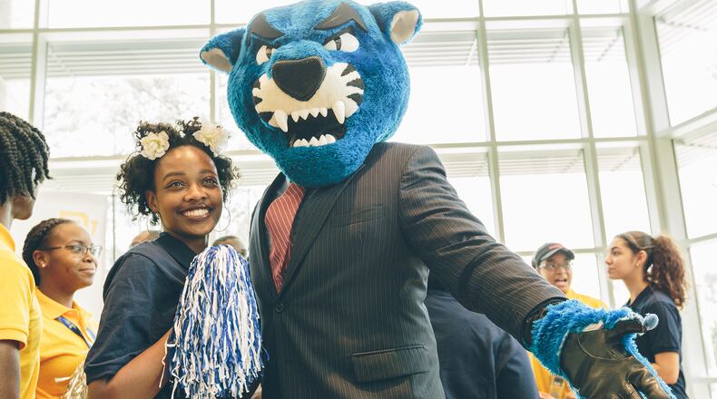 Southwest DeKalb High School senior Kalen Jones poses with Pounce the panther, Georgia State University's mascot, after GSU and State Farm officials announced Wednesday that Kalen was one of 14 students from the school to receive scholarships to the Georgia State University - Perimeter College Decatur campus.