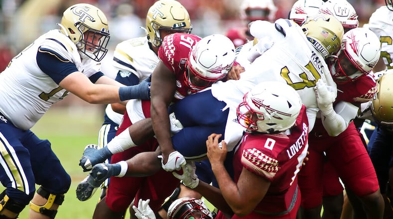 Florida State defenders, including defensive tackle Fabien Lovett (0), lift Georgia Tech running back Hassan Hall (3) off the ground as he tries to runs the ball in the second quarter of an NCAA college football game Saturday, Oct. 29, 2022, in Tallahassee, Fla. (AP Photo/Phil Sears)