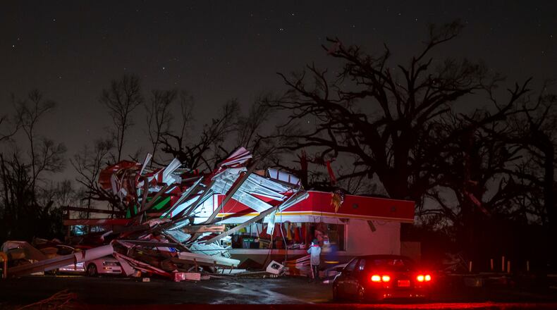 People stop to take a photo of a gas station damaged by an apparent tornado, Sunday, Jan. 22, 2017, in Albany, Ga. Nathan Deal declared a state of emergency in several counties, including Cook, that have suffered deaths, injuries and severe damage from weekend storms. (AP Photo/Branden Camp)