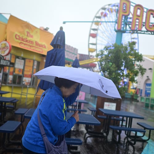 A tourist from China battles the rain on the Santa Monica pier Wednesday, Dec. 24, 2025, in Santa Monica, Calif. (AP Photo/Wally Skalij)