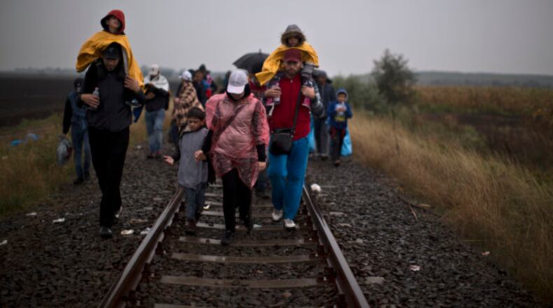 Syrian refugees walk on a railway track toward a makeshift camp for asylum seekers in Roszke, southern Hungary, Thursday, Sept. 10, 2015. Leaders of the United Nations refugee agency warned Tuesday that Hungary faces a bigger wave of 42,000 asylum seekers in the next 10 days and will need international help to provide shelter on its border, where newcomers already are complaining bitterly about being left to sleep in frigid fields. (AP Photo/Muhammed Muheisen)