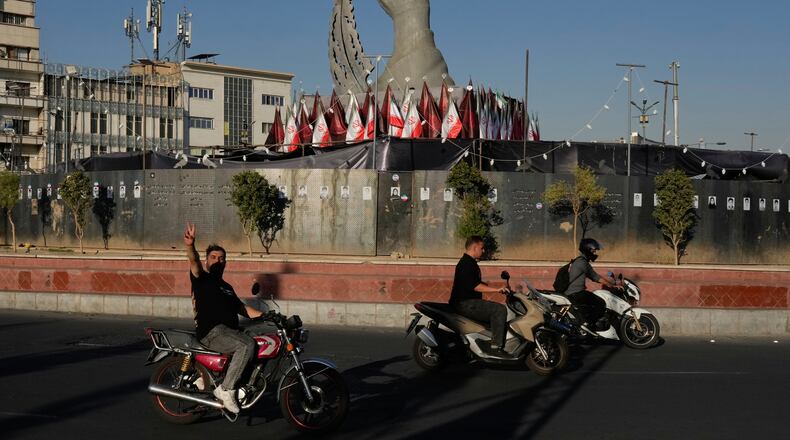 A man reacts to the camera while driving past a monument depicting the clenched fist of the late Iranian Supreme Leader Ayatollah Ali Khamenei, who was killed in the U.S. and Israel strike on Feb. 28, and a missile at the Islamic Revolution square in downtown Tehran, Iran, Tuesday, Sept. 15, 2026. (AP Photo/Vahid Salemi)