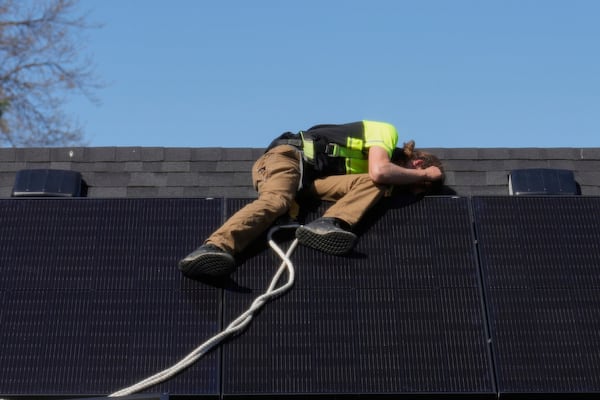 Theodore Tanczuk, of solar installer YellowLite, puts a panel on the roof of a home in Lakewood, Ohio, Wednesday, April 16, 2025. (AP Photo/Sue Ogrocki)
