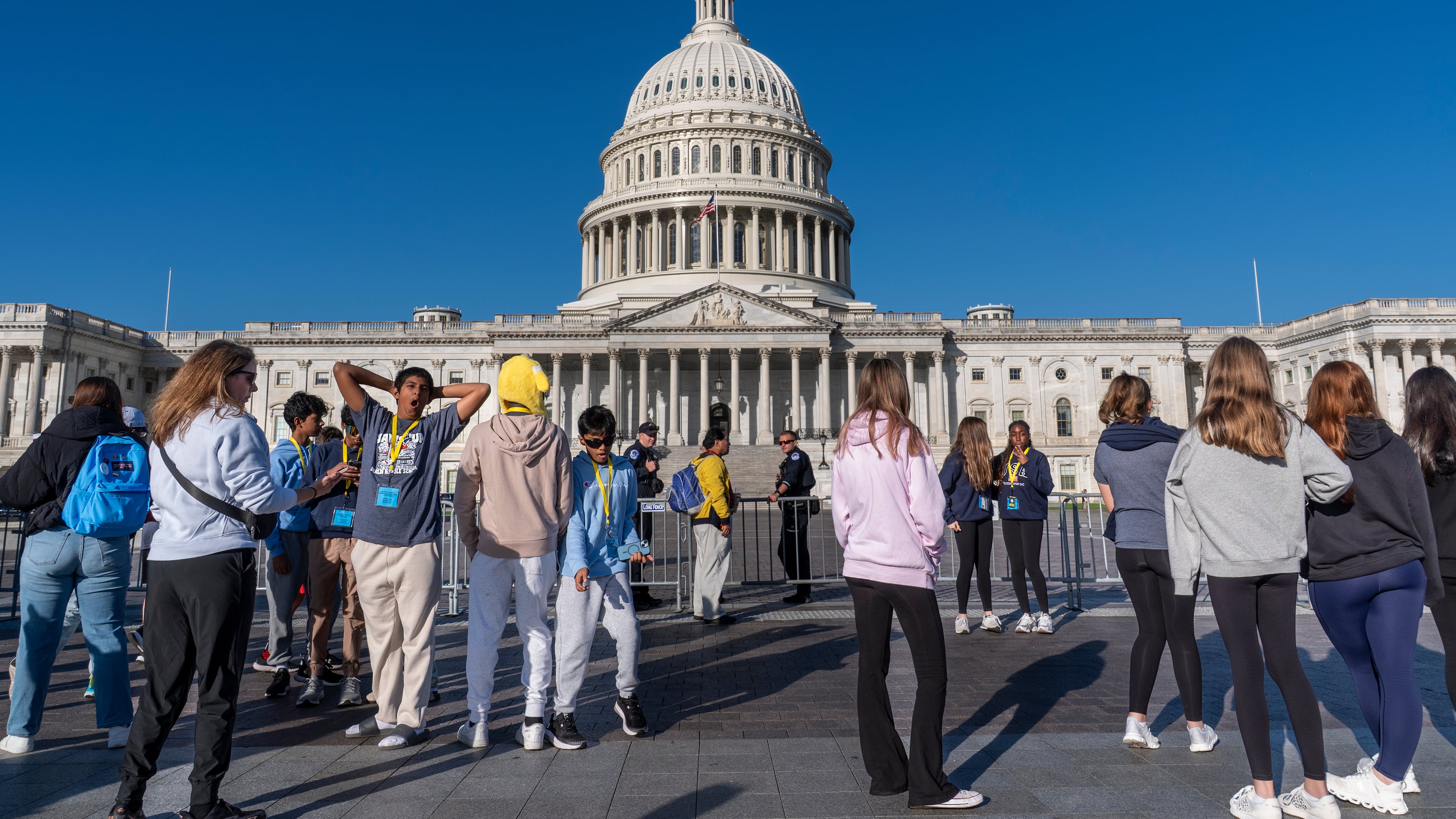 Students from Columbus, Ohio, wait outside a barrier as U.S. Capitol Police watch over the East Plaza where congressional leaders will have a news conferences on the government shutdown at the Capitol in Washington, Wednesday, Oct. 15, 2025. (AP Photo/J. Scott Applewhite)