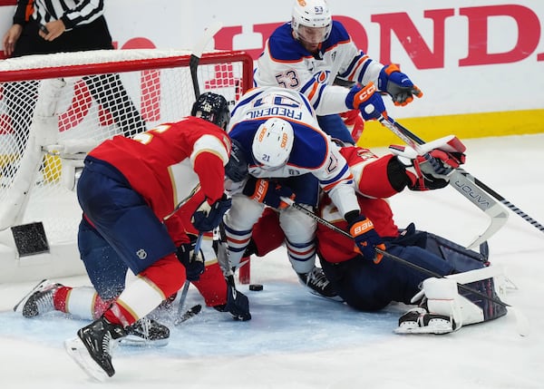 Florida Panthers goalie Sergei Bobrovsky, bottom right, makes a save against Edmonton Oilers' Trent Frederic (21) during the first overtime period in Game 4 of the NHL hockey Stanley Cup Final in Sunrise, Fla., Thursday, June 12, 2025. (Nathan Denette/The Canadian Press via AP)