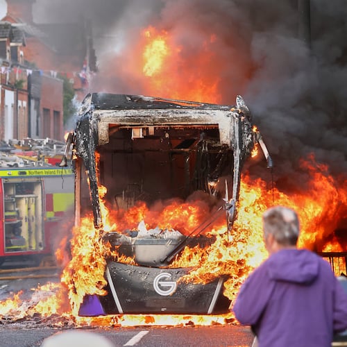People watch as firemen arrive to put out vehicle that was set alight during a protest in East Belfast following a stabbing incident in Belfast, Tuesday, June 9, 2026. (AP Photo/Peter Morrison)