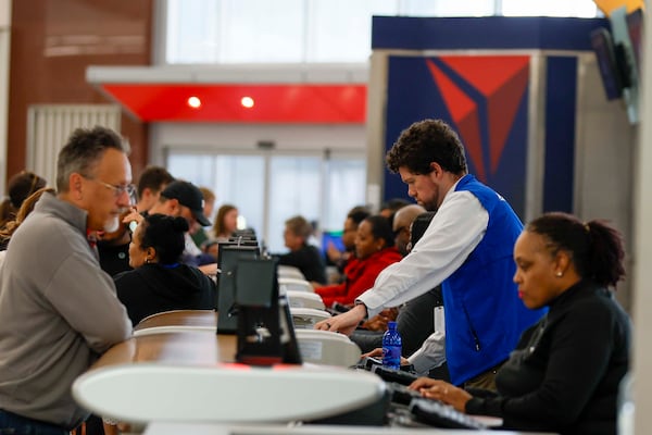 Agents from Delta Air Lines assist travelers at Hartsfield-Jackson Atlanta International Airport on Sunday. (Miguel Martinez/AJC)